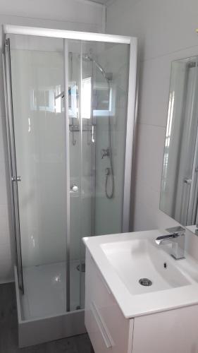La salle de bains blanche est pourvue d'une douche et d'un lavabo. dans l'établissement Le chalet de La Treille, à Marseille