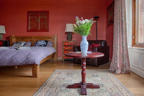 um quarto com uma cama e um vaso de flores sobre uma mesa em Netherbrae em Edimburgo