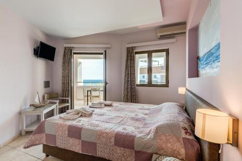 a bedroom with a bed and a view of the ocean at Alkionis Beach Hotel Apartments in Sfakaki