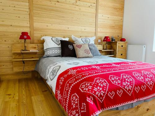 Un dormitorio con una cama roja y blanca con paredes de madera. en La Sabaudia en Saint-Pierre-dʼEntremont