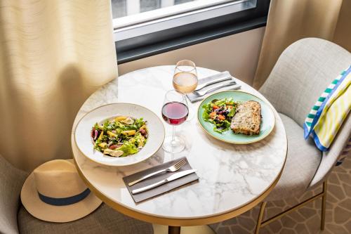 a table with two plates of food and wine glasses at OKKO Hotels Nice Aéroport in Nice