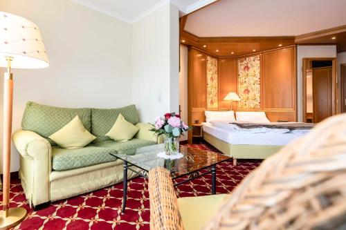 ein Hotelzimmer mit einem Sofa und einem Bett in der Unterkunft Hotel Restaurant Waldsägmühle in Pfalzgrafenweiler