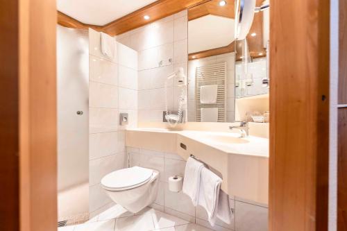 a white bathroom with a toilet and a sink at Hotel Restaurant Waldsägmühle in Pfalzgrafenweiler