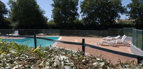 une piscine avec des chaises et un court de tennis dans l'établissement Mobil Home Fradin Parc de loisirs, à Talmont-Saint-Hilaire