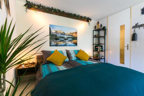 Un dormitorio con una cama azul con almohadas amarillas en Spirit Apartments - Studio 1 - Küche - Parkplatz en Engelberg