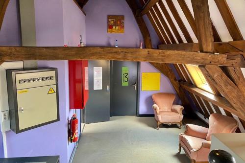 a room with purple walls and a staircase with chairs at Antwerp City Hostel in Antwerp