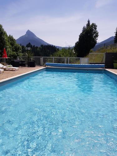 a large blue swimming pool with a mountain in the background at Hotel Le Beau Site in Saint-Pierre-de-Chartreuse