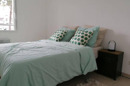 ein Bett mit blauen und grünen Kissen darauf in der Unterkunft T2 entier - Hyper centre - Cosy home in Grenade-sur-Garonne