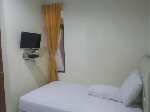 een slaapkamer met een bed en een tv aan de muur bij Modern Indekos Cilegon Syariah RedPartner in Grogol