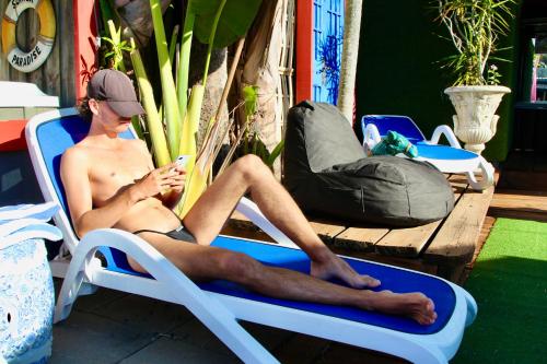 a man sitting in a chair in front of a pool of water at Hideaway Noosa Men Only Beach Resort in Peregian Beach