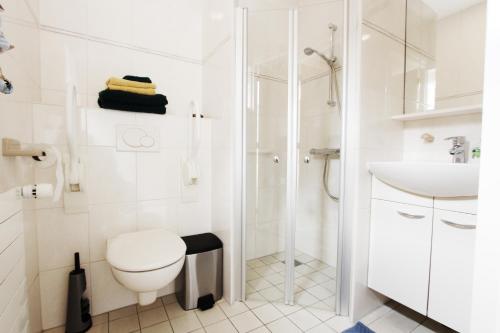 uma casa de banho branca com um WC e um chuveiro em Valhalla em Egmond-Binnen