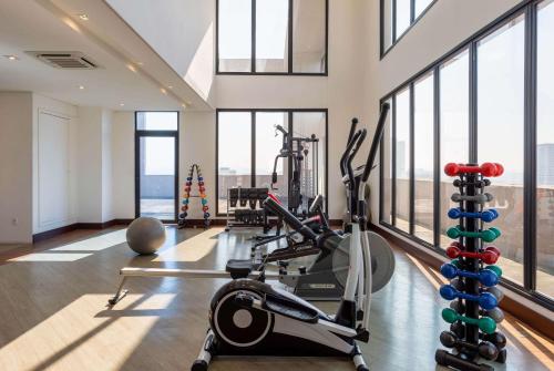 a gym with treadmills and ellipticals in a building with windows at Ramada Encore by Wyndham São Paulo Osasco in Osasco