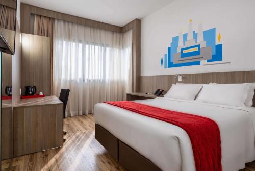 a hotel room with a large bed and a desk at Ramada Encore by Wyndham São Paulo Osasco in Osasco