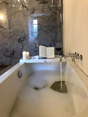a bath tub with a book and a glass of wine at L’Aurora in Todi