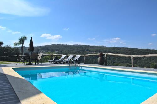 a swimming pool with chairs and a person sitting next to it at Quinta dos Lagos in Marco de Canaveses