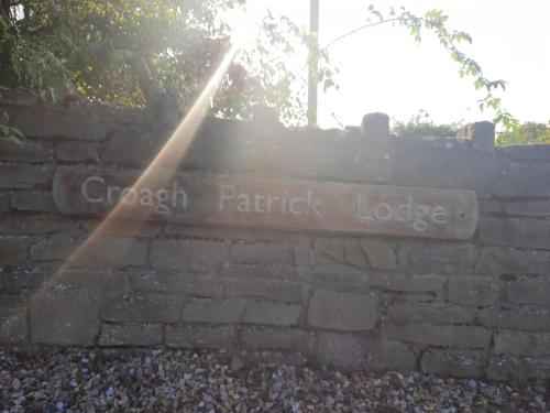 a sign on a brick wall with a rainbow at Croagh Patrick Lodge Apartment in Westport