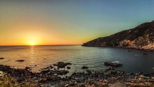 a sunset over a body of water with a mountain at Lefteris Rooms in Kámbos