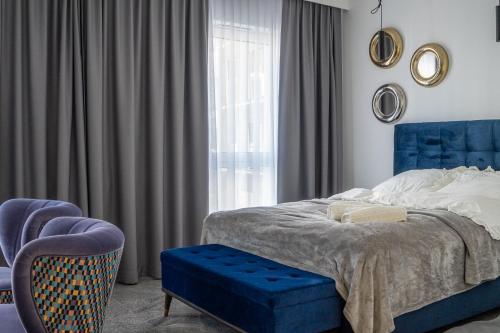 ein Schlafzimmer mit einem blauen Bett, einem Stuhl und einem Fenster in der Unterkunft Roadway Silniczna z garażem podziemnym in Kielce