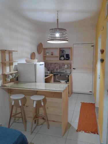 a kitchen with a counter with a refrigerator and two stools at Formosinha in Baía Formosa