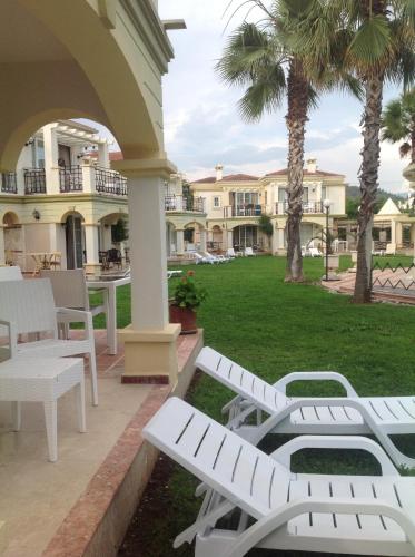 a patio with white benches and a lawn with palm trees at Villa B&D in Fethiye