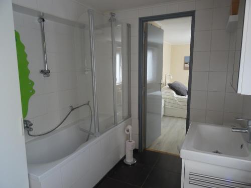 a bathroom with a shower and a tub and a sink at Kustverhuur, Breskens, Nijverheidstraat 11 in Breskens