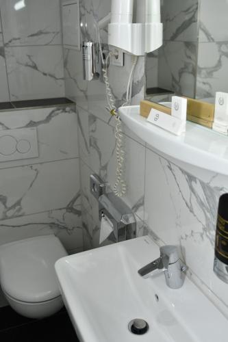 a white bathroom with a toilet and a sink at Hotel Münchner Hof in Frankfurt