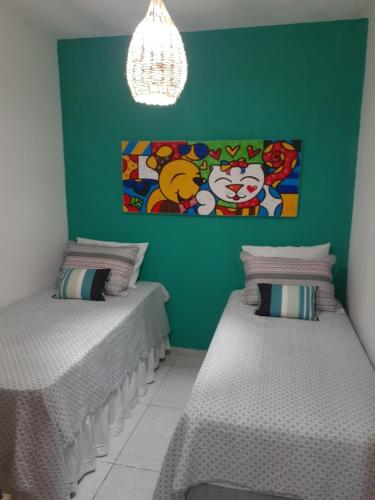 two beds in a room with a green wall at Formosinha in Baía Formosa