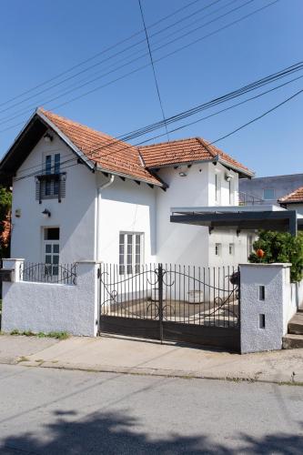a white house with a gate on a street at Sweet Home in Valjevo