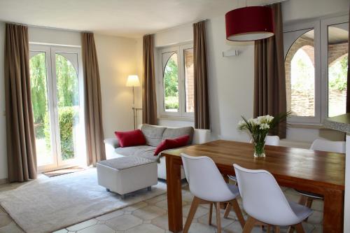 ein Wohnzimmer mit einem Holztisch und weißen Stühlen in der Unterkunft B Apartment in Bierbeek