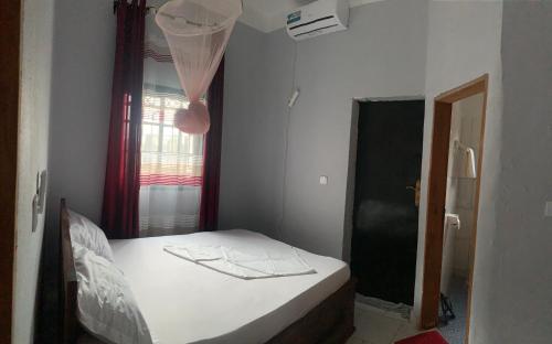 a small bedroom with a bed and a window at Residence SVET in Kribi