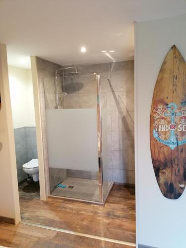 a bathroom with a shower with a surfboard on the wall at La résinière in Salles