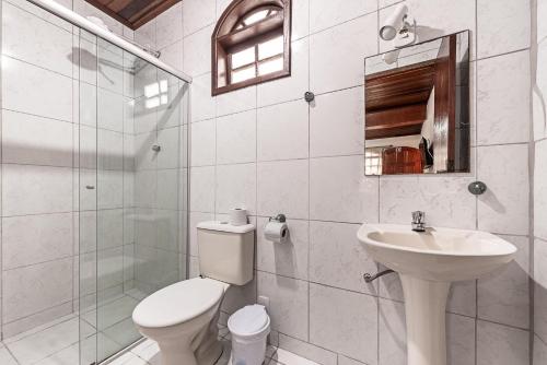 a white bathroom with a toilet and a sink at Pousada Acqua Marina in Paraty