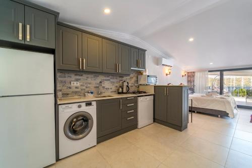 a kitchen with green cabinets and a washer and dryer at Nakas Suites in Fethiye