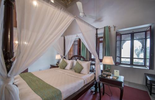 a bedroom with a bed with a canopy at The Laxmi Niwas Palace in Bikaner