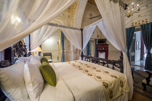 1 dormitorio con 1 cama blanca con dosel en The Laxmi Niwas Palace, en Bikaner