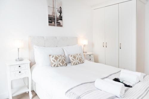 a white bedroom with a large white bed with pillows at City Stay Apartments - Vizion in Milton Keynes