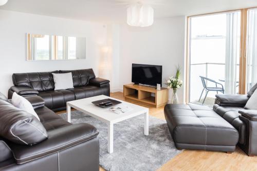 a living room with a leather couch and a table at City Stay Apartments - Vizion in Milton Keynes