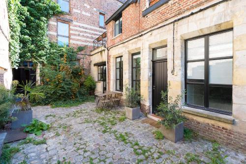 un bâtiment en briques avec une cour ornée de plantes en pot dans l'établissement La Corderie, à Lille
