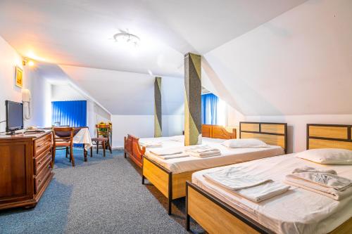 a hotel room with three beds and a table at Motel Dasiana in Târgu Jiu