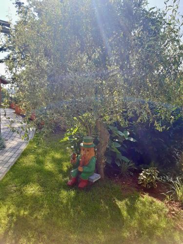 a teddy bear sitting in the grass under a tree at Chata U lesa in Svoboda nad Úpou