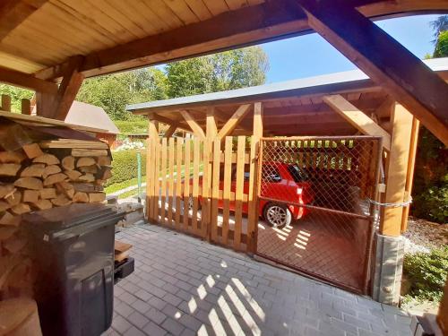 a wooden chicken coop with a red car in it at Chata U lesa in Svoboda nad Úpou