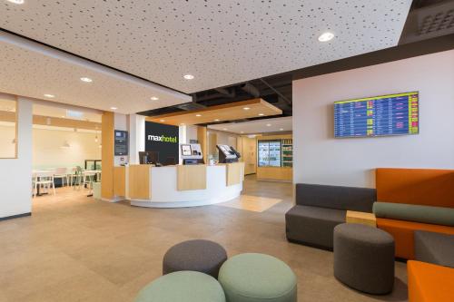 an office lobby with a check in counter and stools at Maxhotel Amsterdam Airport Schiphol in Hoofddorp