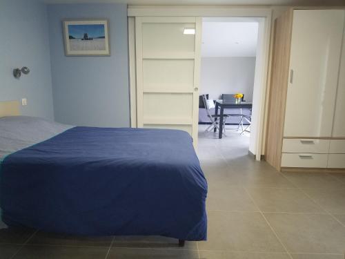 Un dormitorio con una cama azul y una mesa en Un pied devant l'autre, 