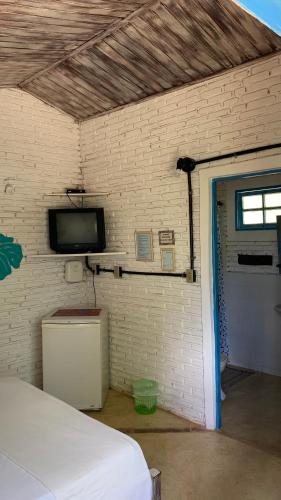 a bedroom with a bed and a tv on a brick wall at Refúgio do Corsário-Imbassai-Ba in Imbassai