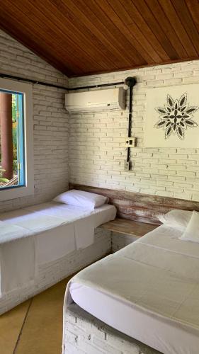 two beds in a small room with a window at Refúgio do Corsário-Imbassai-Ba in Imbassai