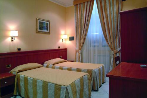 a hotel room with two beds and a window at Hotel Meridiana in Rome