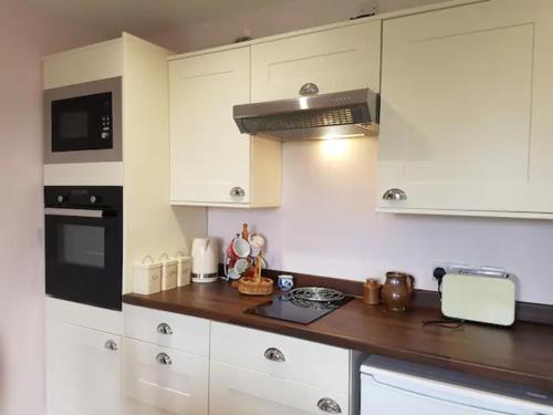 a kitchen with white cabinets and a counter top at Stag Cottage in Ilkeston