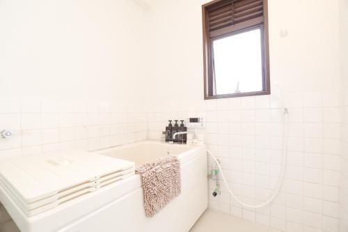 a white bathroom with a sink and a window at Fukuoka Condominium in Fukuoka