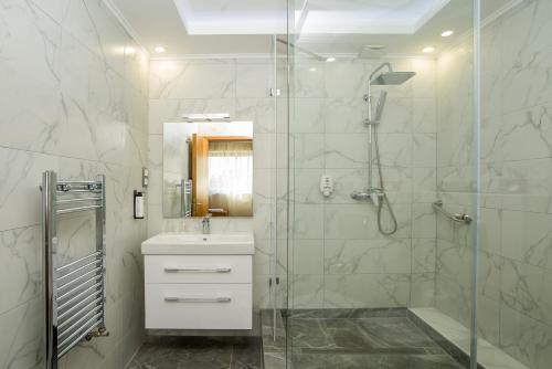 a bathroom with a sink and a shower with a glass door at Marmara Hotel Budapest in Budapest