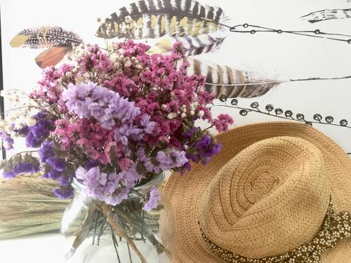a vase of purple flowers and a hat on a table at Le jardin Chamberlin, Maison d'hôtes in Savigny-sur-Orge